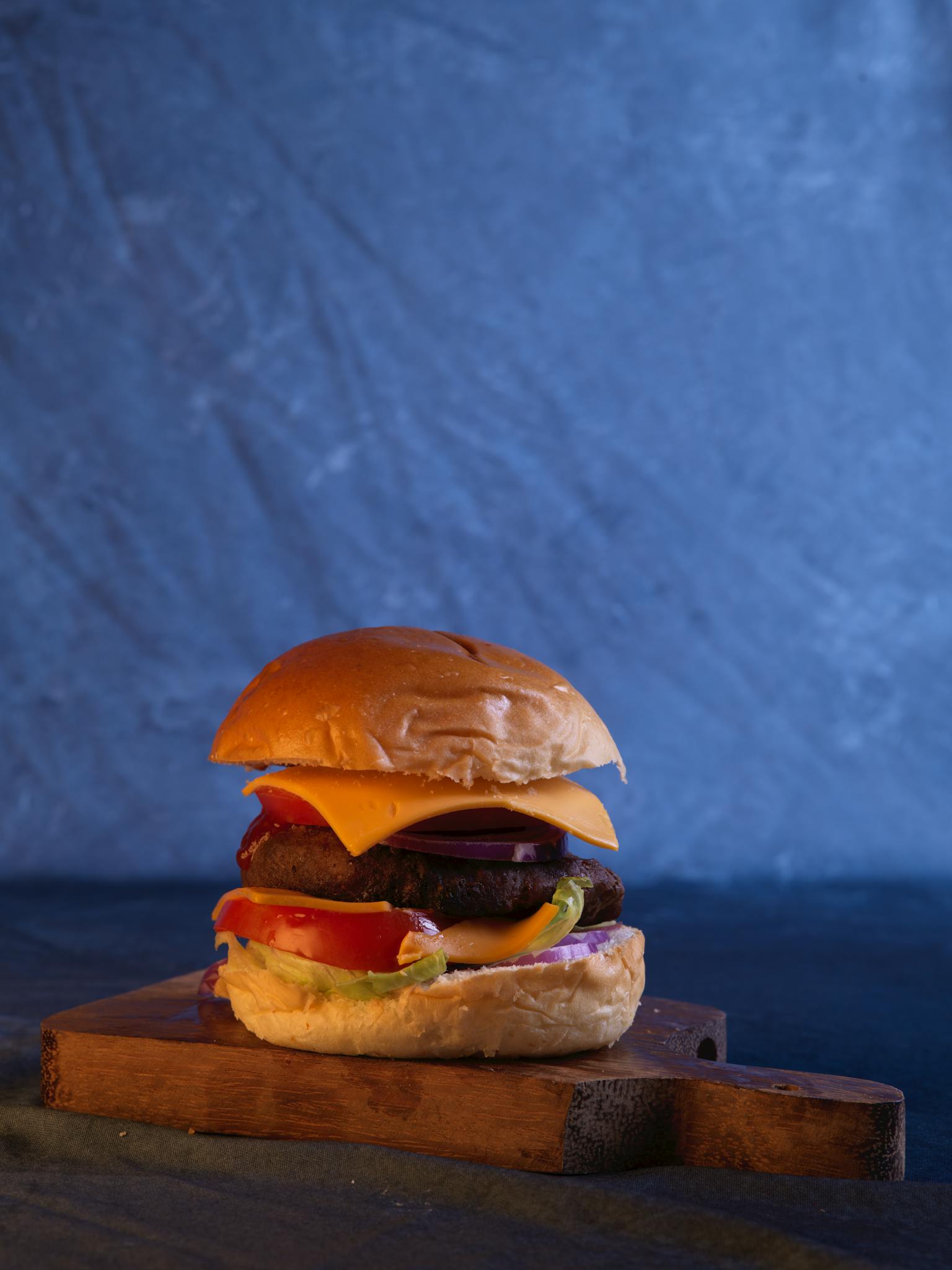 Delicious cheeseburger with fresh ingredients on a wooden board, perfect for gourmet lovers.